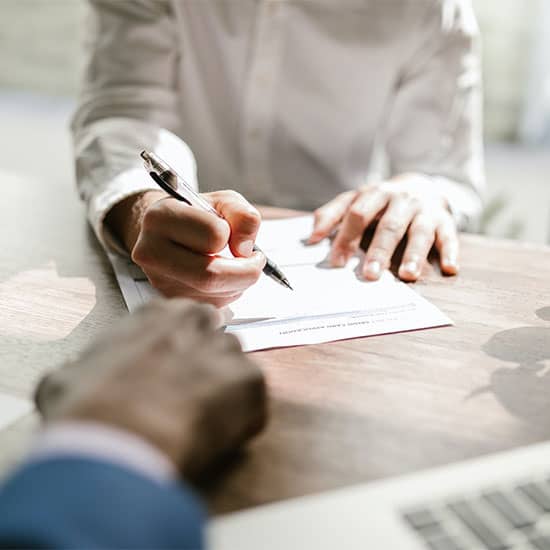 A woman’s holding a pen getting ready to sign an agreement.