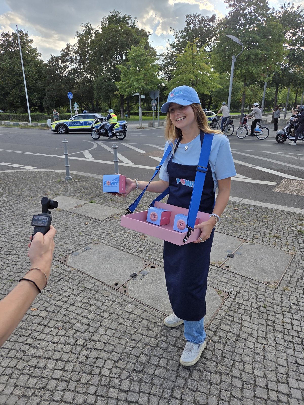 Ponut-Sampling auf der Straße: Promoterin verteilt Ponut-Boxen mit Infobox zur Prostatakrebs-Früherkennung