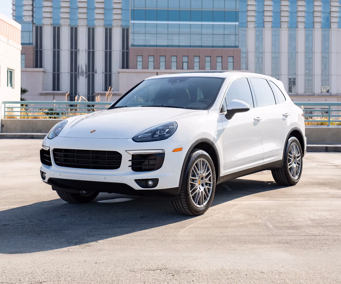 White luxury SUV parked outdoors in front of a modern building.