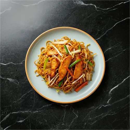 Plate of stir-fried noodles with pieces of cooked chicken, bean sprouts, and vegetables on a black marble surface.