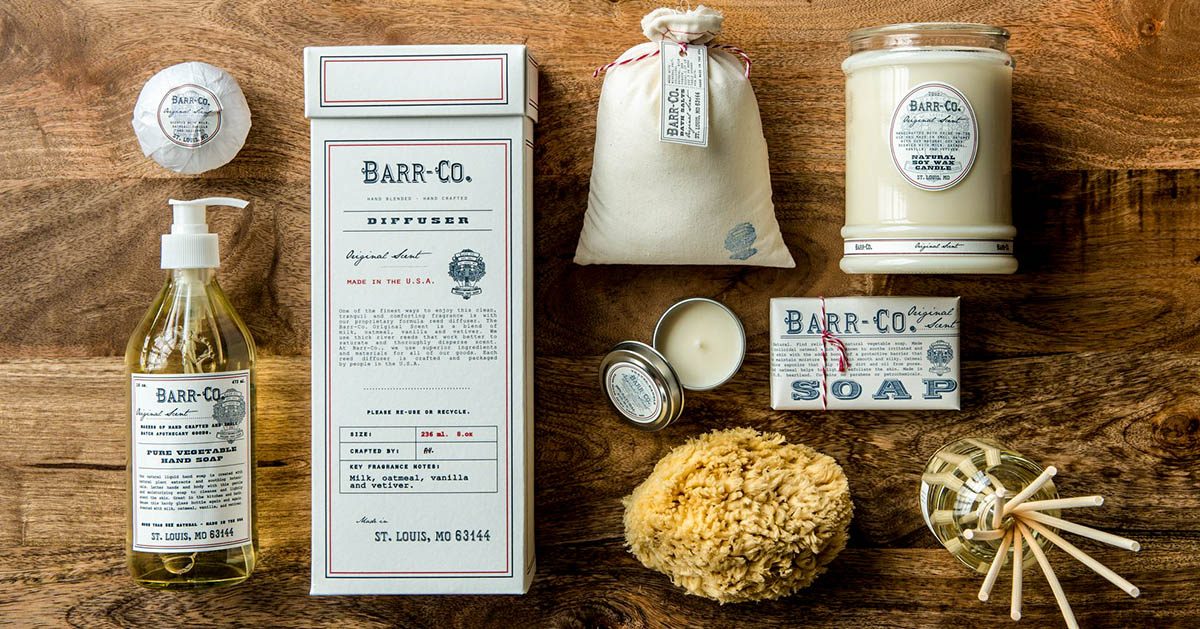 Barr-Co natural scented products including hand soap, diffuser, candle, soap bar, sponge, and fragrance sticks on wood.