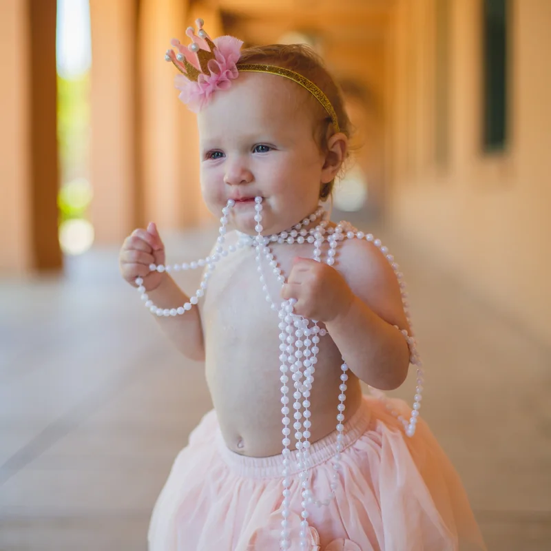 Baby girl in a tutu and pearl necklaces at a kids photoshoot