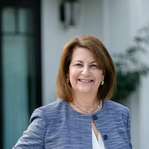 Smiling businesswoman in a blue tweed jacket, outdoor headshot