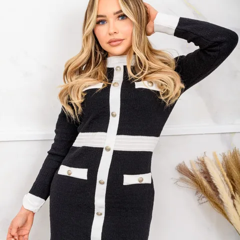 Fashion model in a black and white knit dress against a marble wall