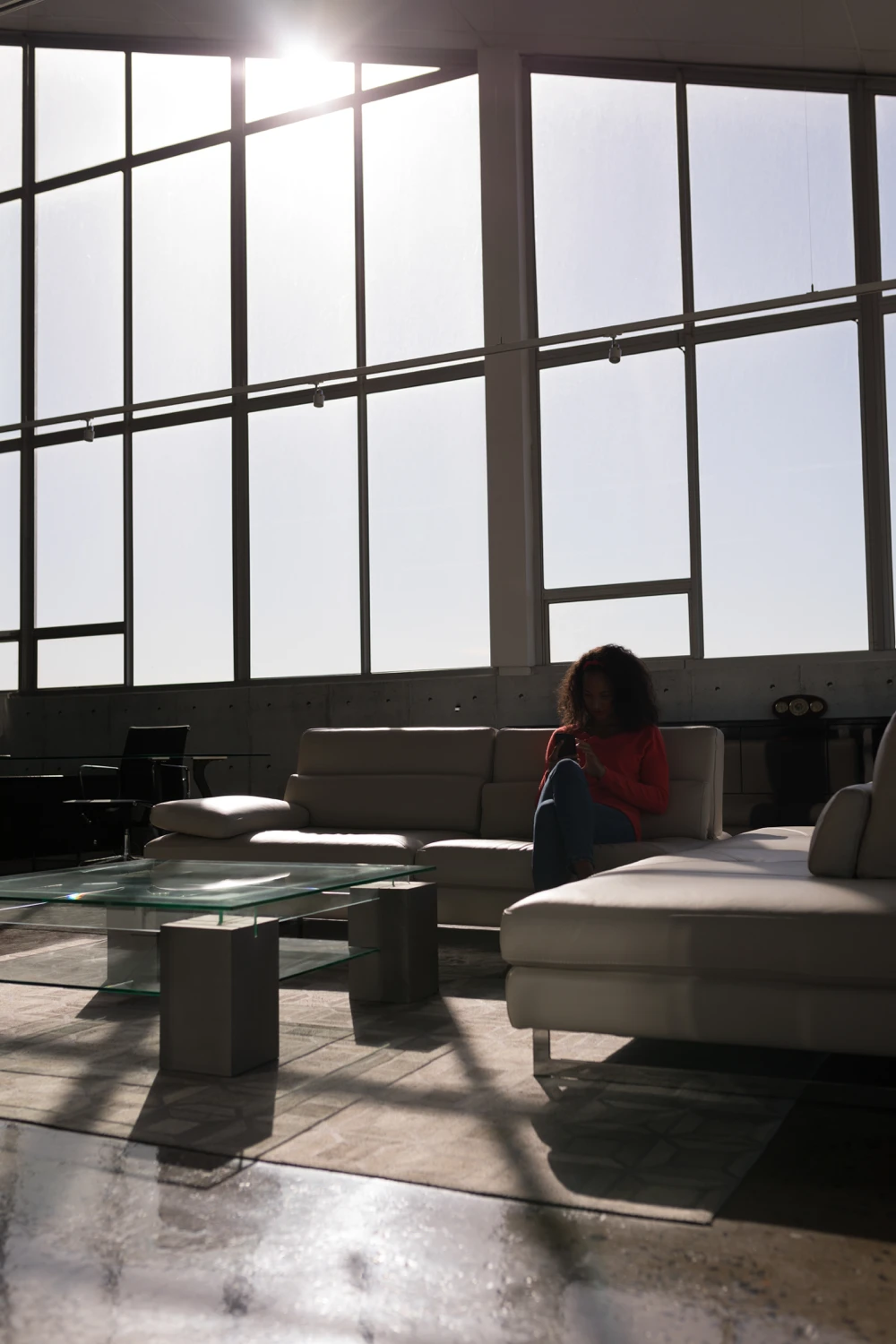 Lumière intense traversant une grande baie vitrée dans un salon moderne avec canapé blanc.