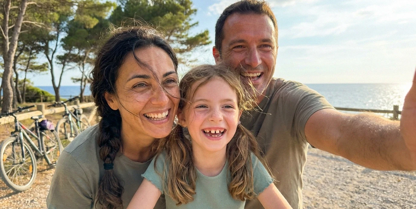 Famiglia felice all'aperto in estate mostra sorrisi sani e naturali dopo la ricostruzione dei denti.