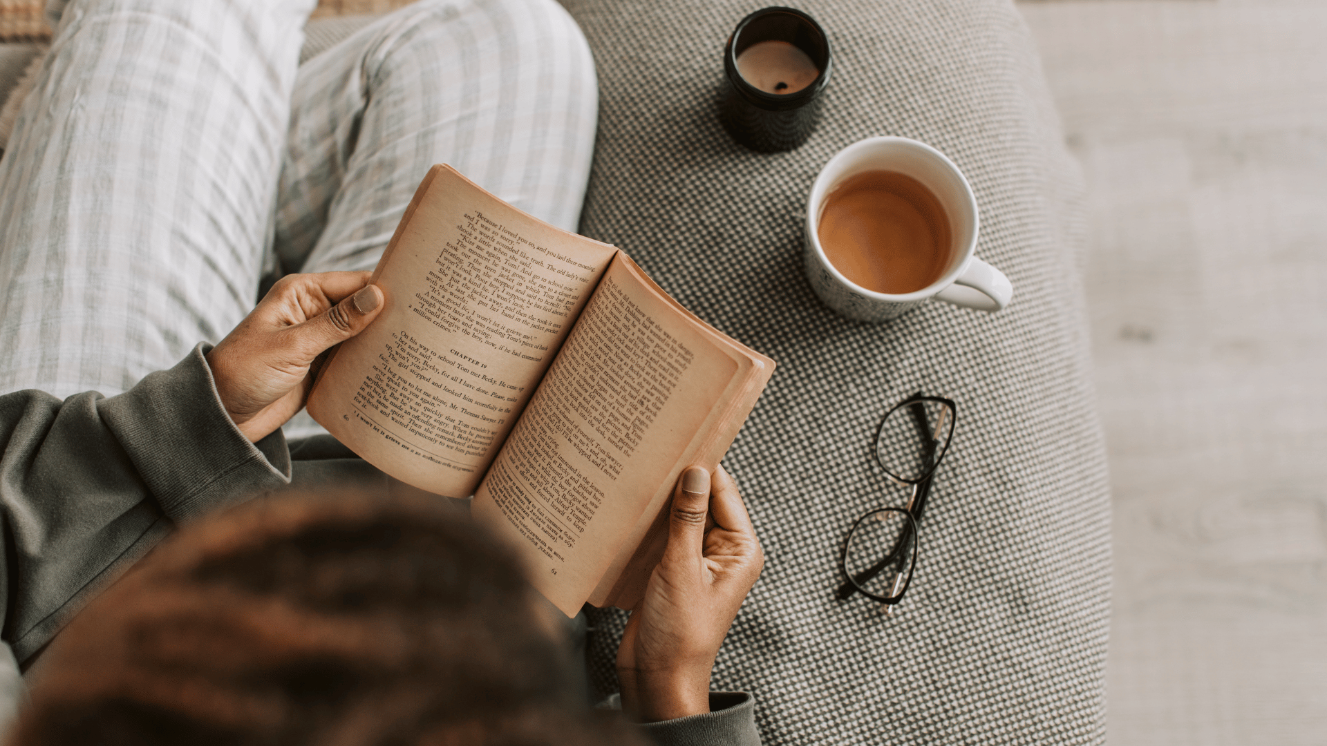Overhead view of a person reading a book and drinking coffee