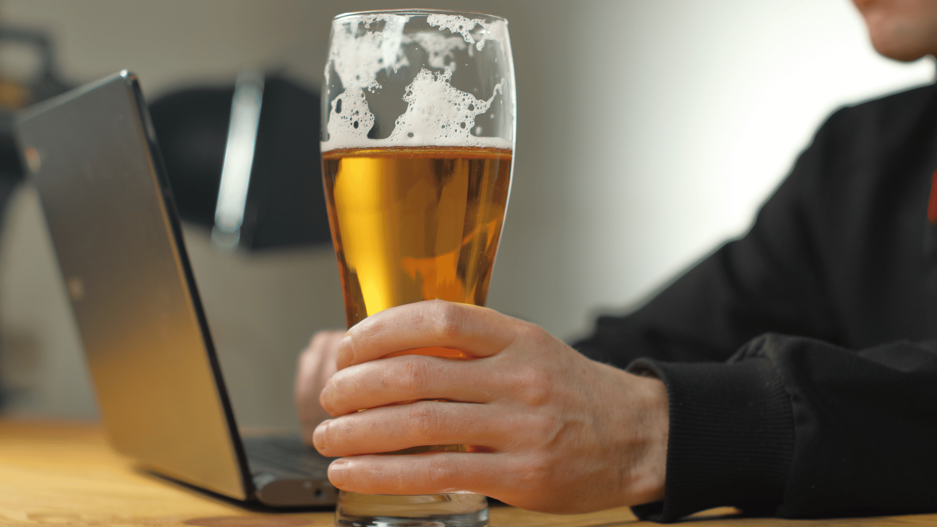 Person holding a beer while on their laptop