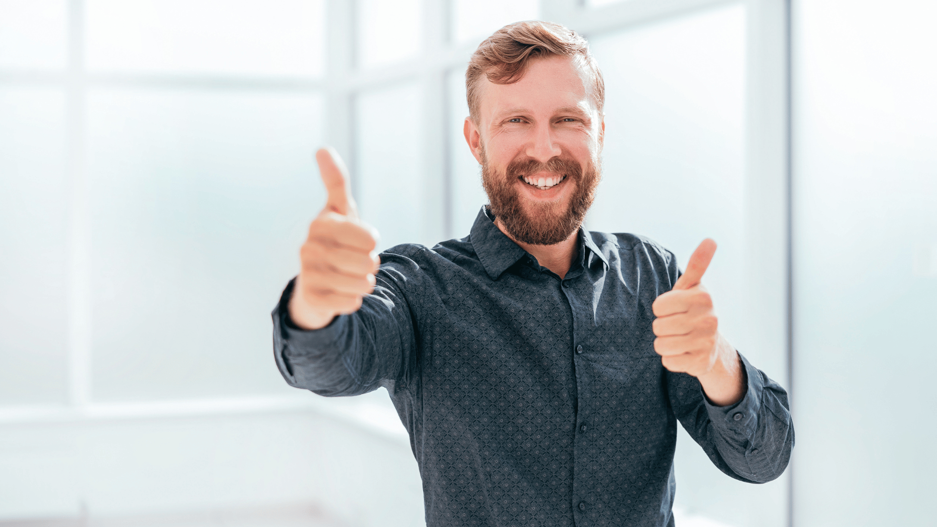 Bearded man in button-up shirt giving double thumbs-up