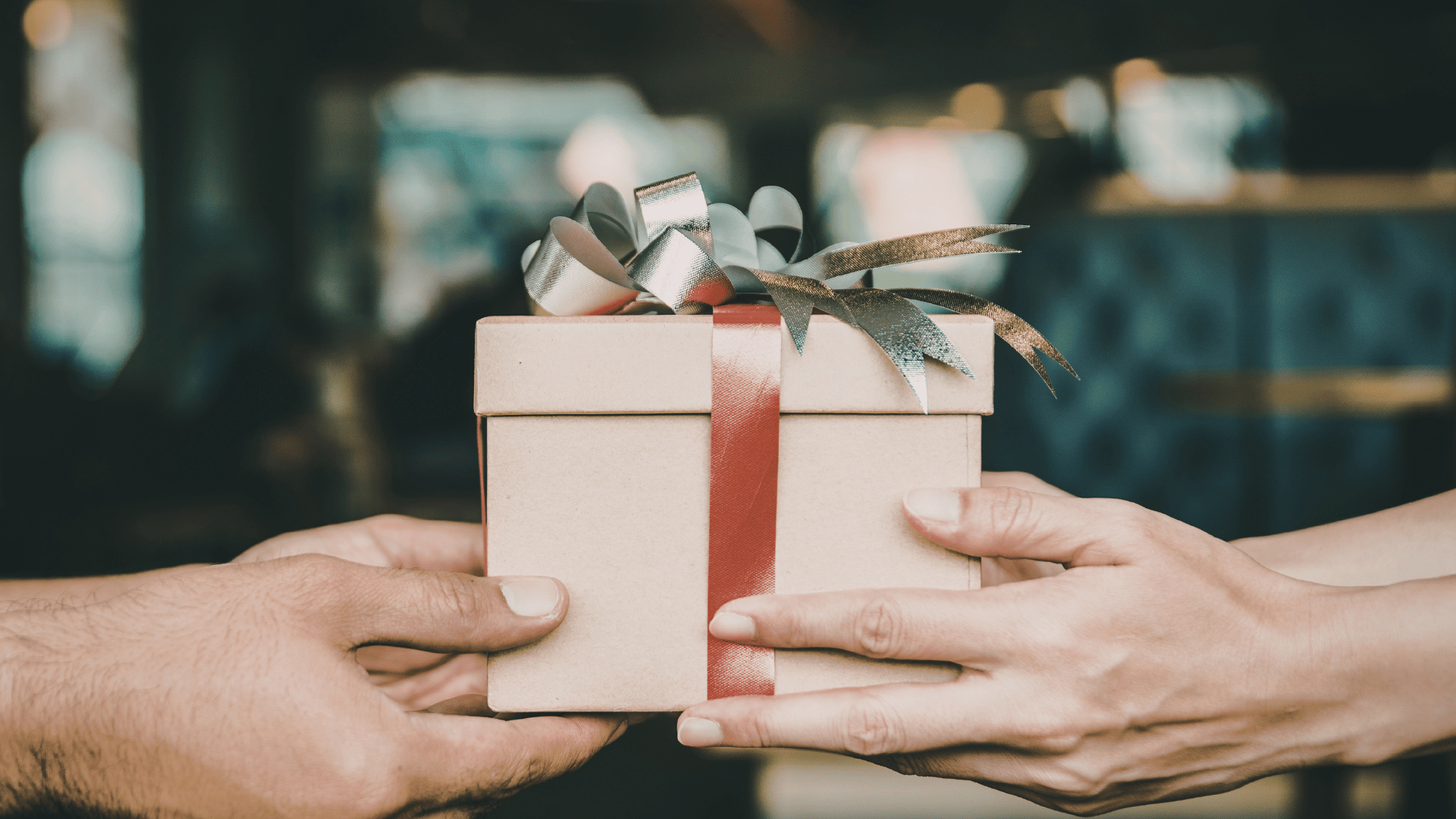 A person handing a gift box to another person