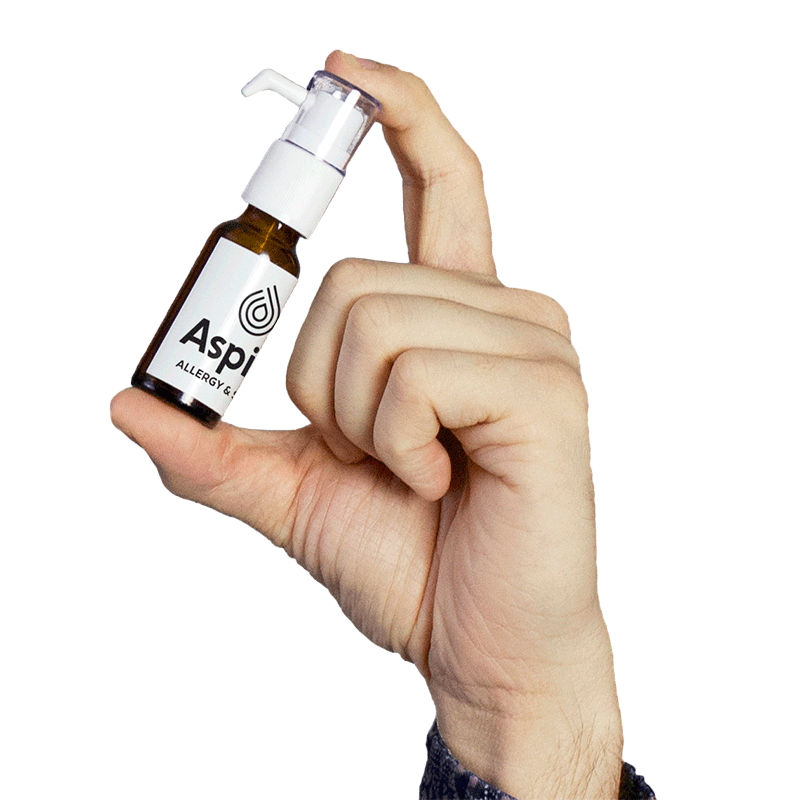 Hand holding a small brown bottle of Allergy Drops from Aspire Allergy & Sinus.
