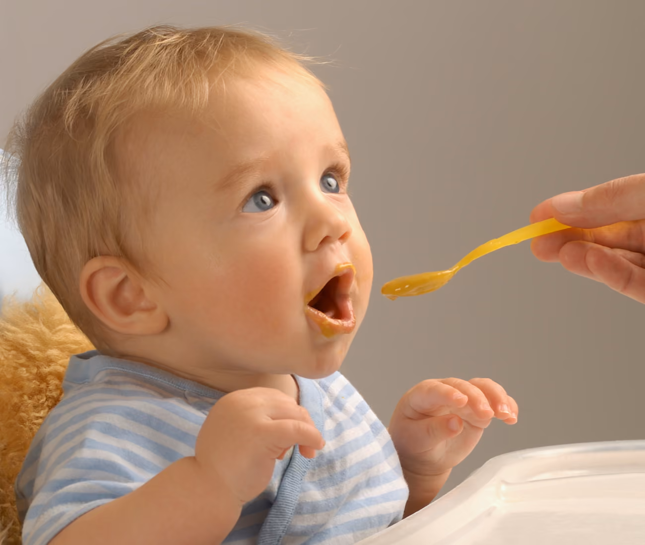 A smiling baby ready to try their first bite of solid food