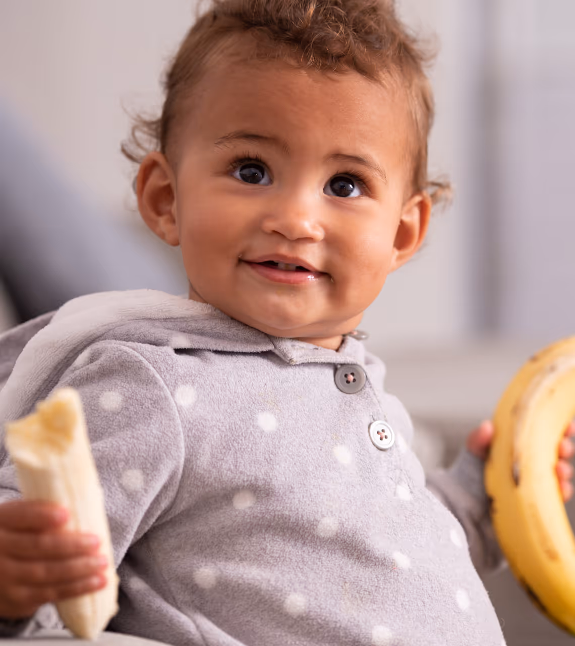 A baby holding a piece of banana