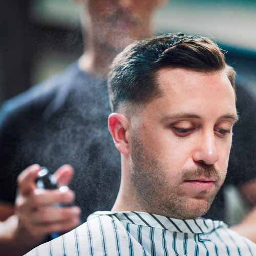 Man is sprayed with cologne after receiving haircut and shave