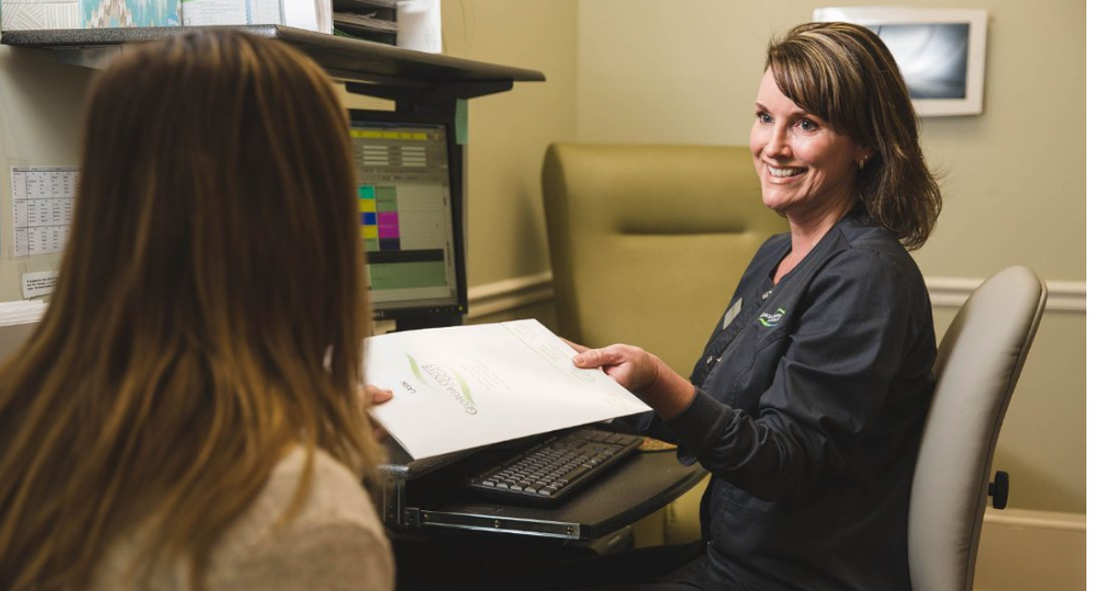 An admin hands a patient a welcome folder
