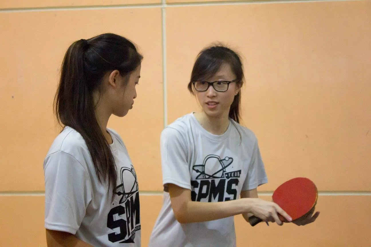 two women standing next to each other holding ping pong paddles