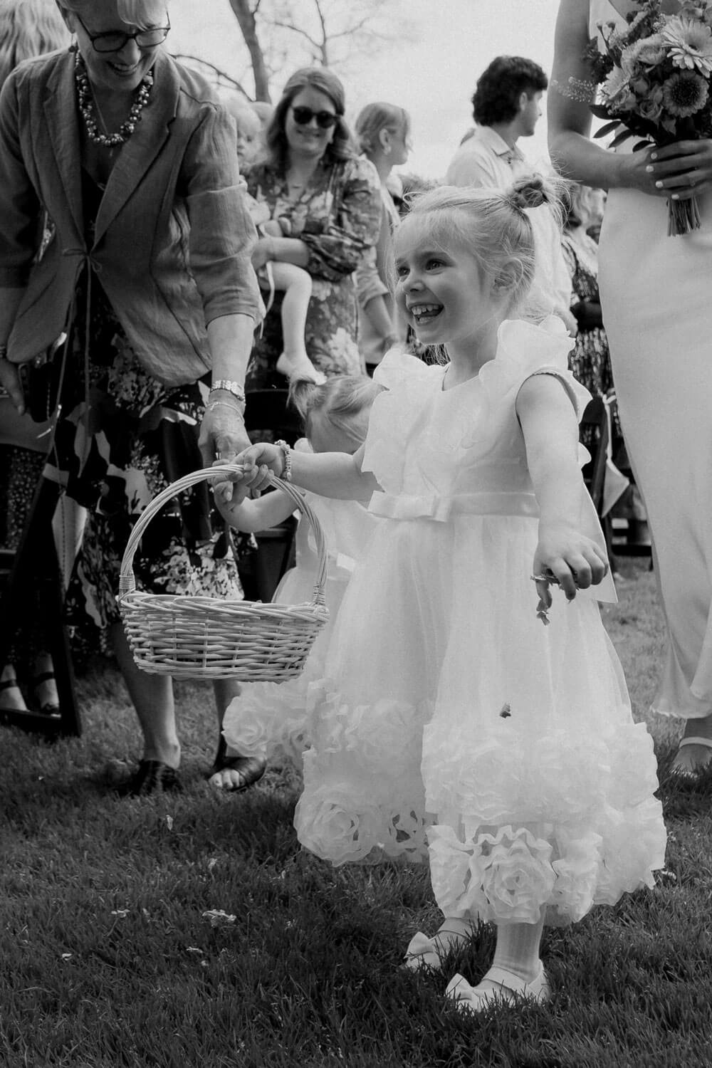 The Red Barn wedding photographer capturing flower girl walking in with a big smile