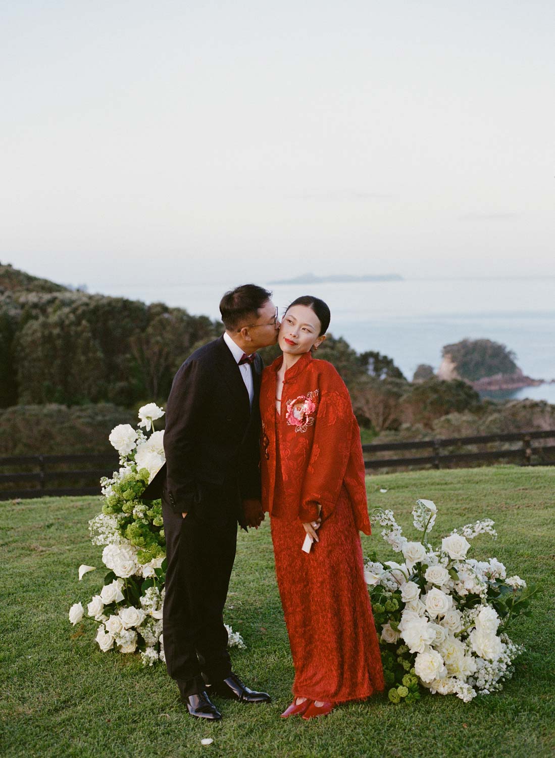 Bride and groom dressed in Chinese wedding outfits kiss during sunset photoshoot