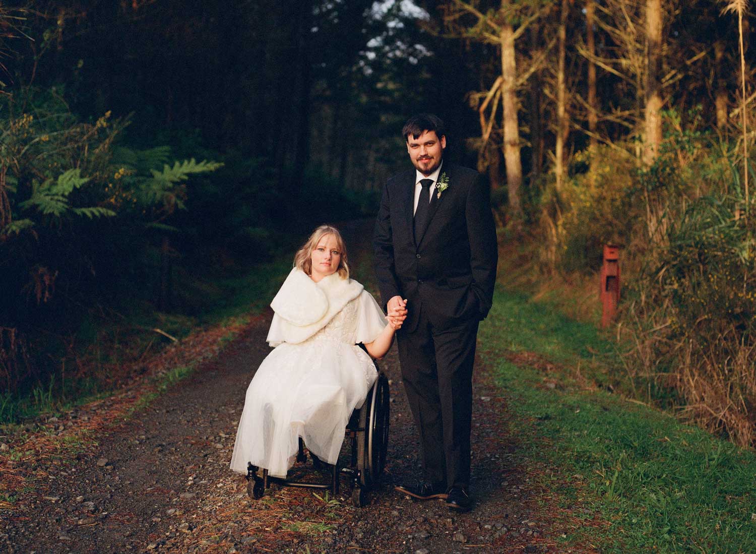 A bride in a wheelchair and groom holding hands shot on 120 film
