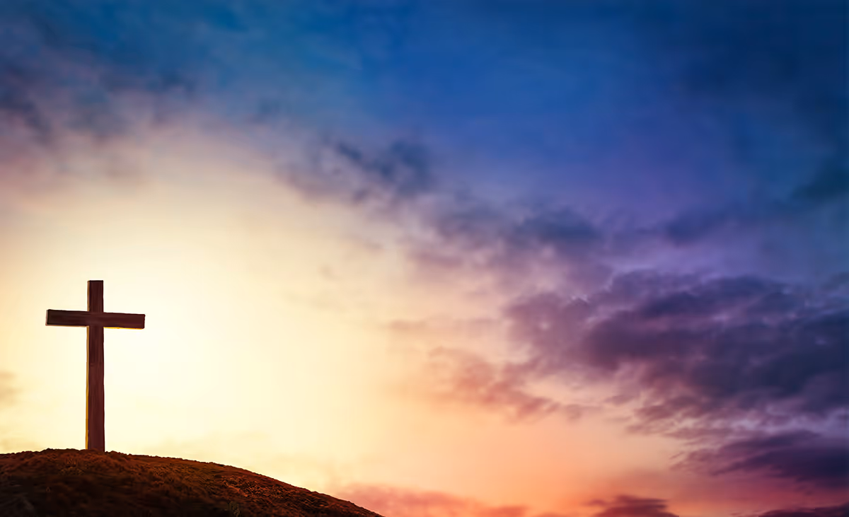 A cross on a hill during a morning sunrise