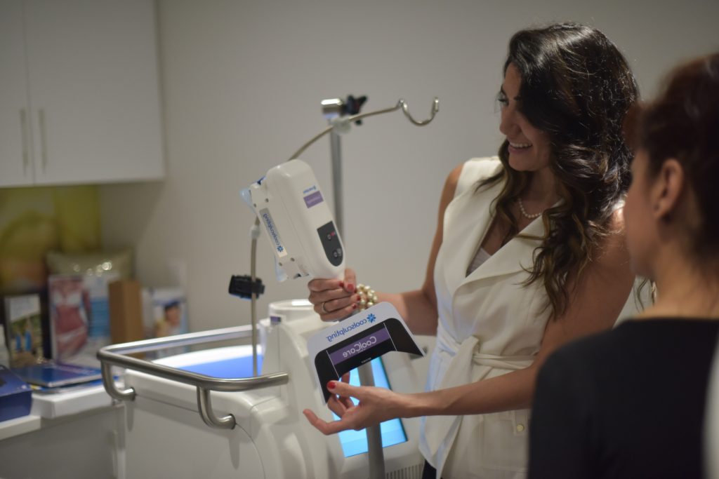 Photo of a woman showing a coolsculpting machine to a woman