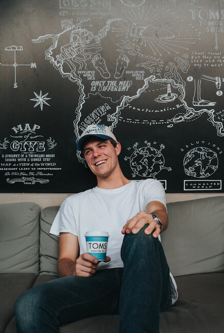 A person laughing with coffee in his hand