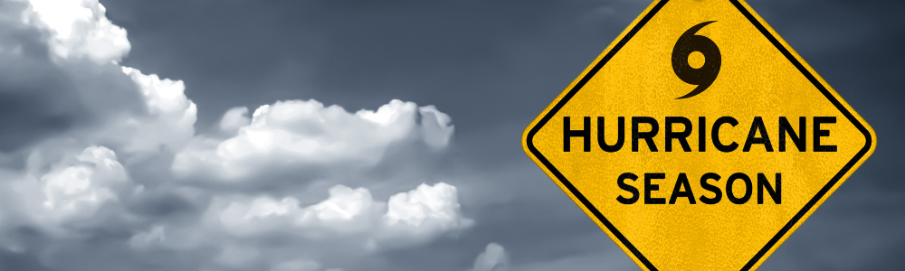 Dark sky with clouds and bright yellow warning sign that says "Hurricane Season"