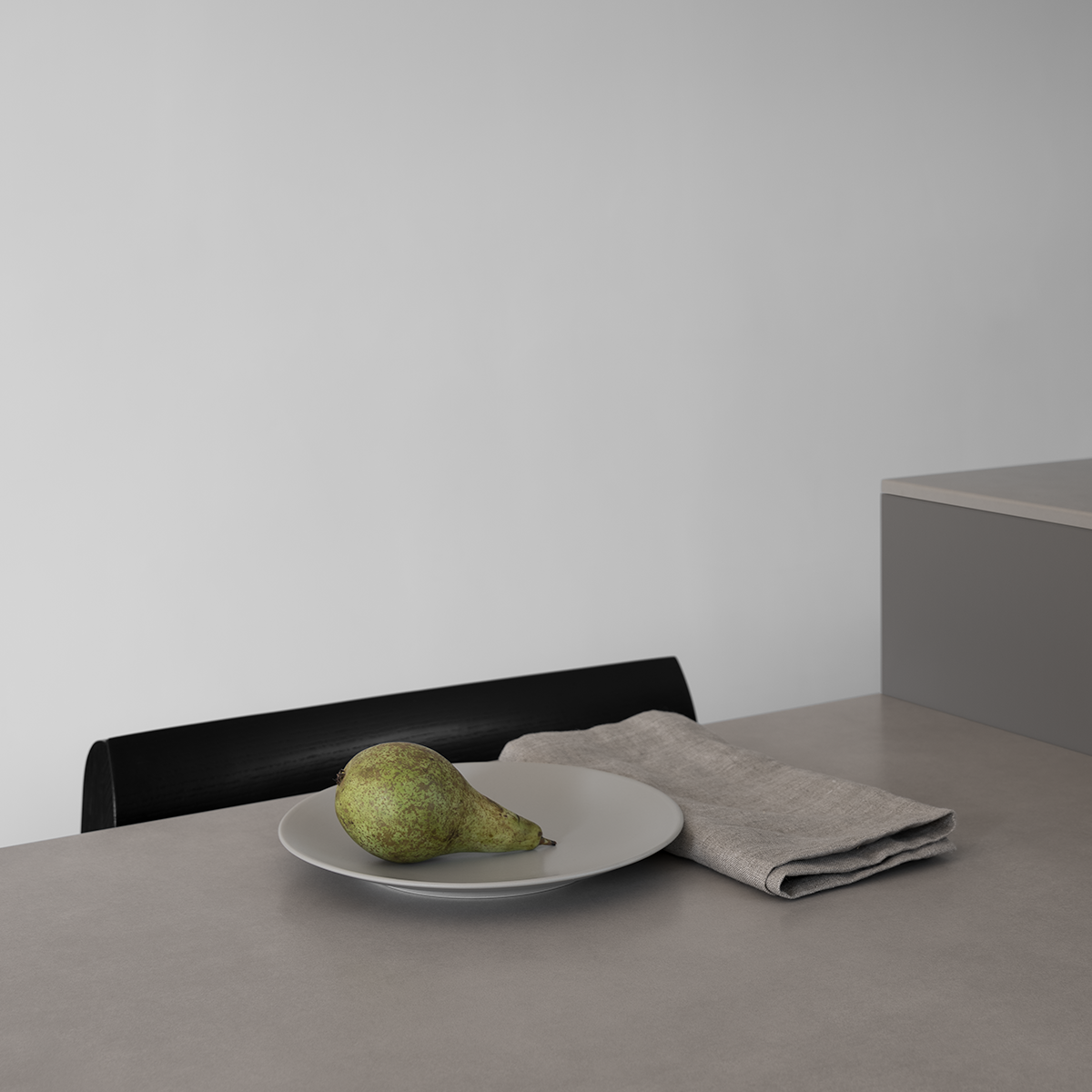 Custom modern sintered stone dining table in light grey, black modern Scandinavian dining chair, pear on a plate, linen napkin