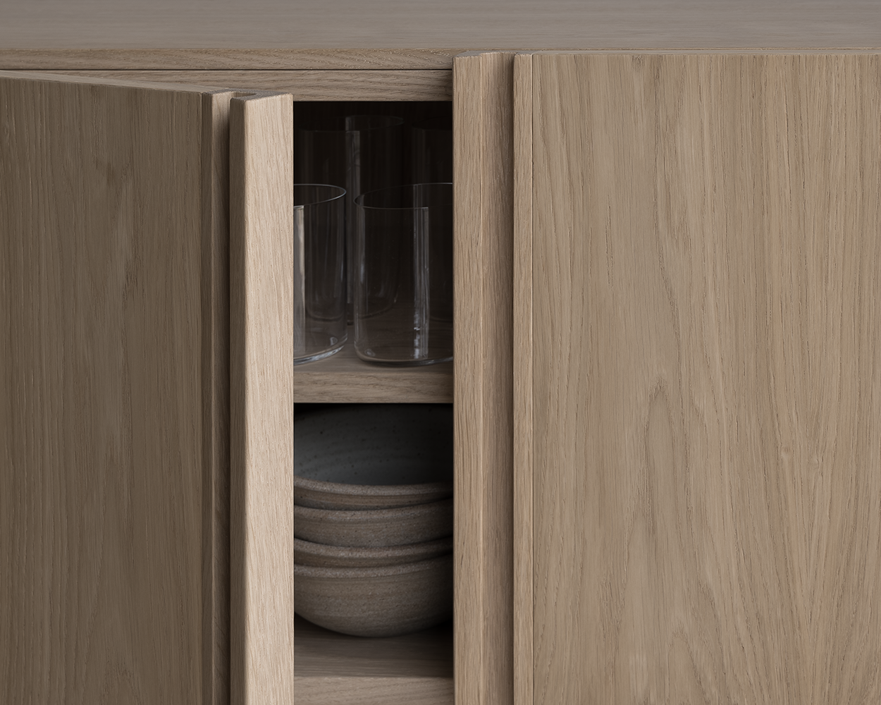 Bleached oak modern Scandinavian sideboard with open door showing glassware and bowls