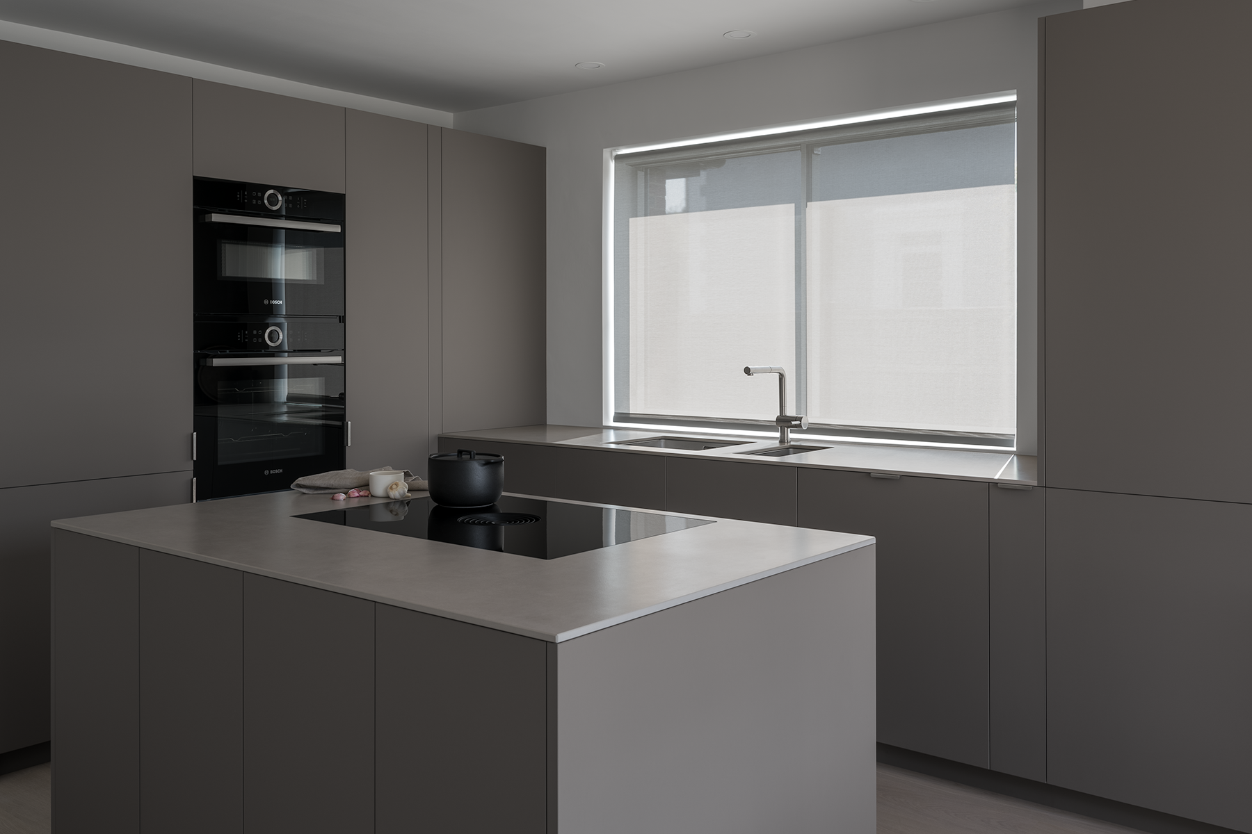 Minimal modern Japanese style open plan kitchen with island, bleached oak floor, white walls, grey brown cabinets, sintered stone worktop, black Japanese cooking pot