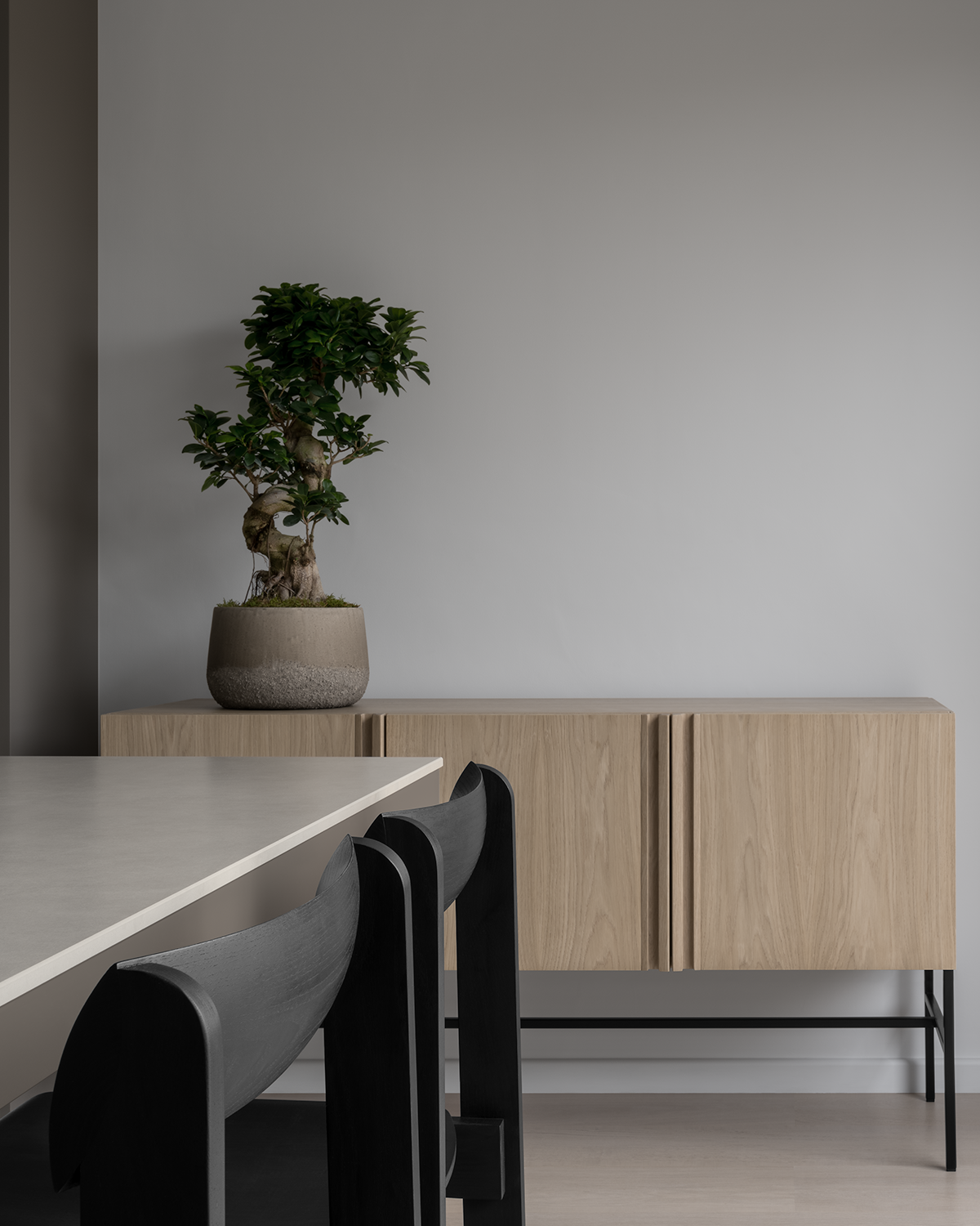 Modern Japanese minimal dining room with bleached oak floor, white walls, sintered stone dining table, black Scandinavian wood dining chairs, oak sideboard and bonsai tree