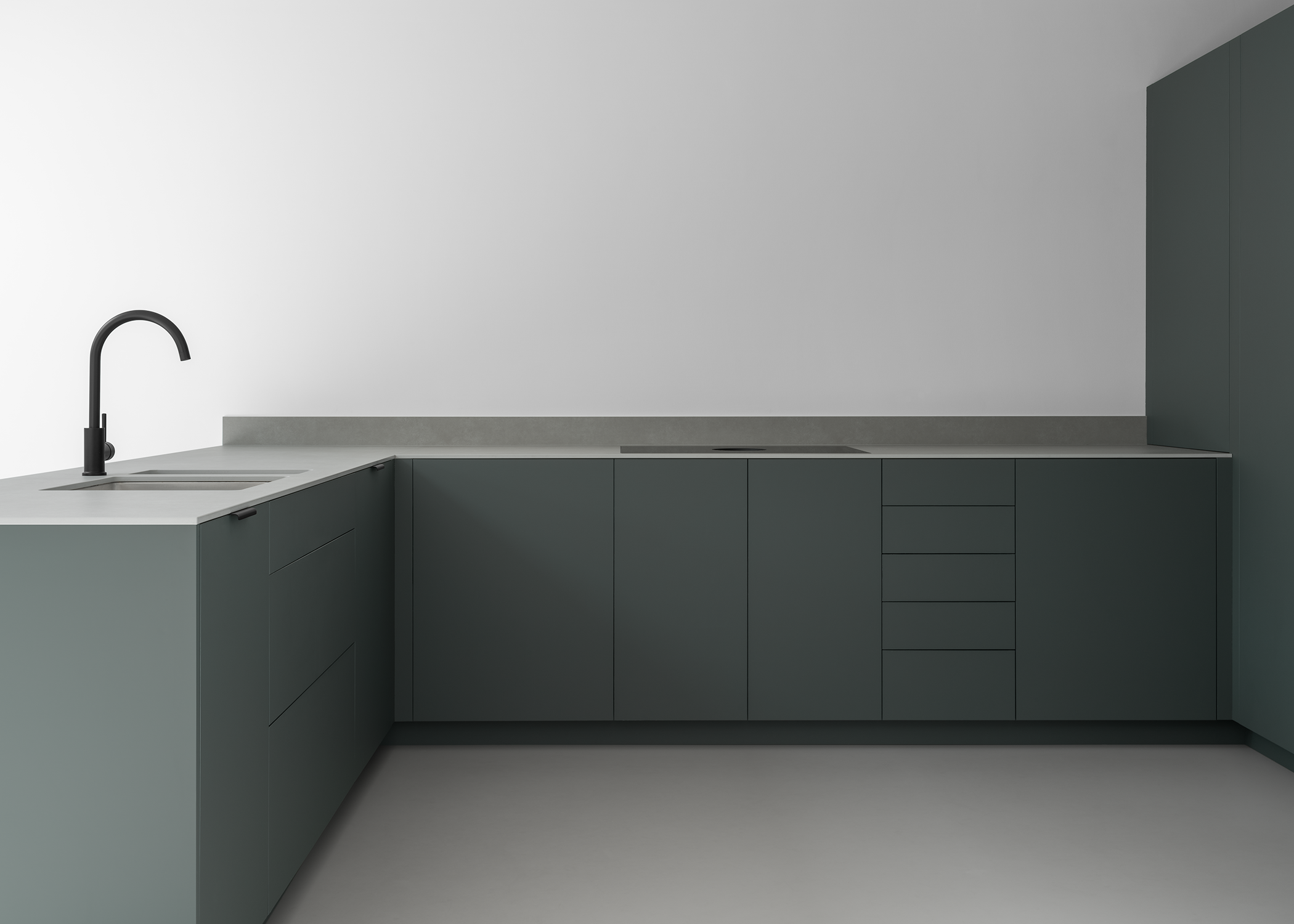 Modern ultra minimal Japanese style kitchen with white walls, grey resin floor, dark green-grey cabinets, slim textured grey stone work surface and black tap.