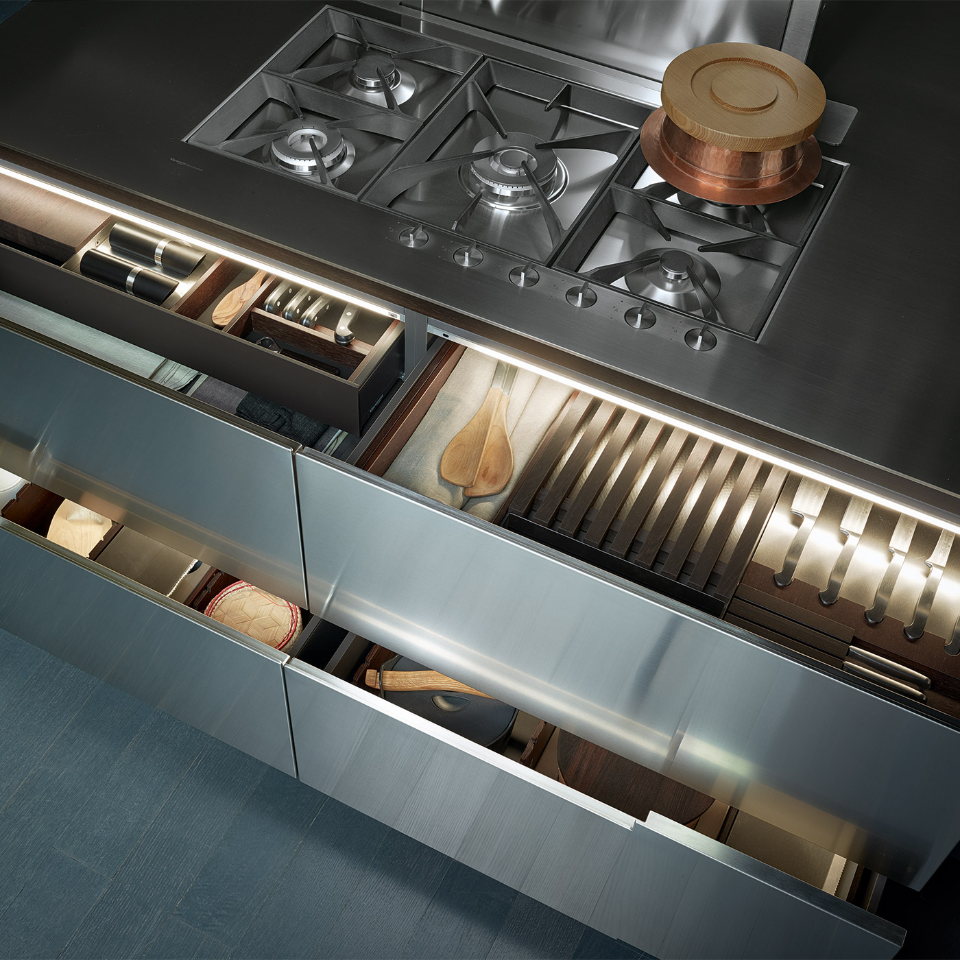 Open storage drawers of minimal kitchen by Poliform. Metal fronts, lined wood compartments and integrated lighting.