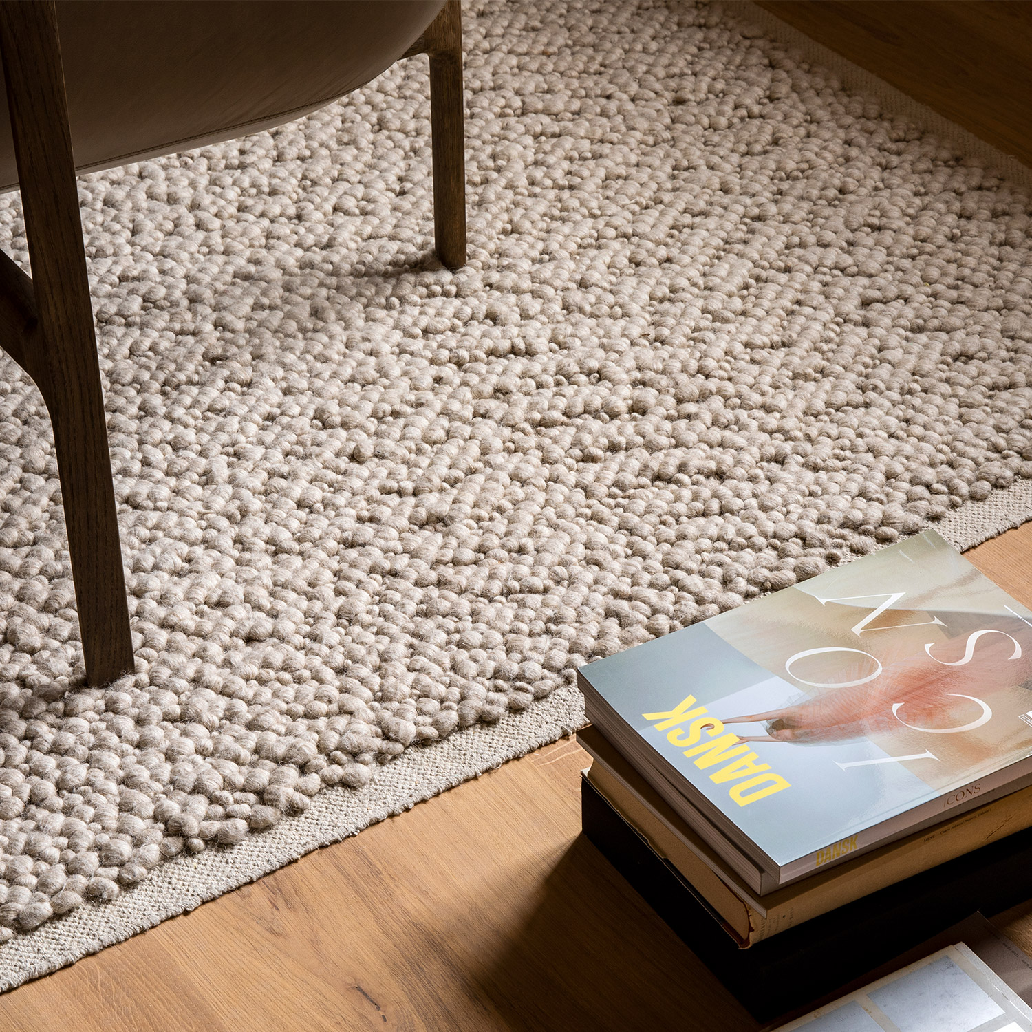 textured cream rug on teak floor with art magazines