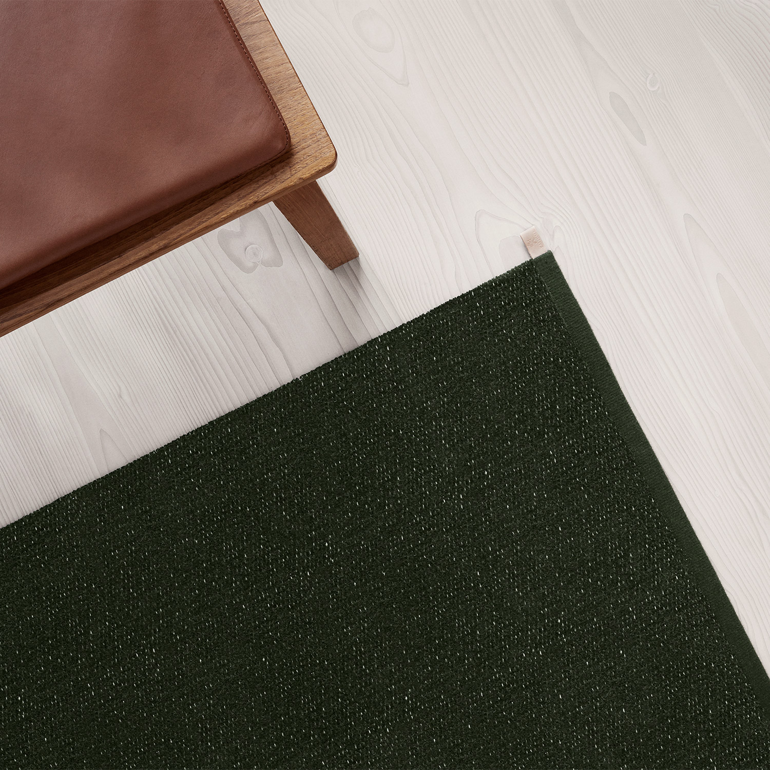 dark green chenille rug and brown leather wooden bench