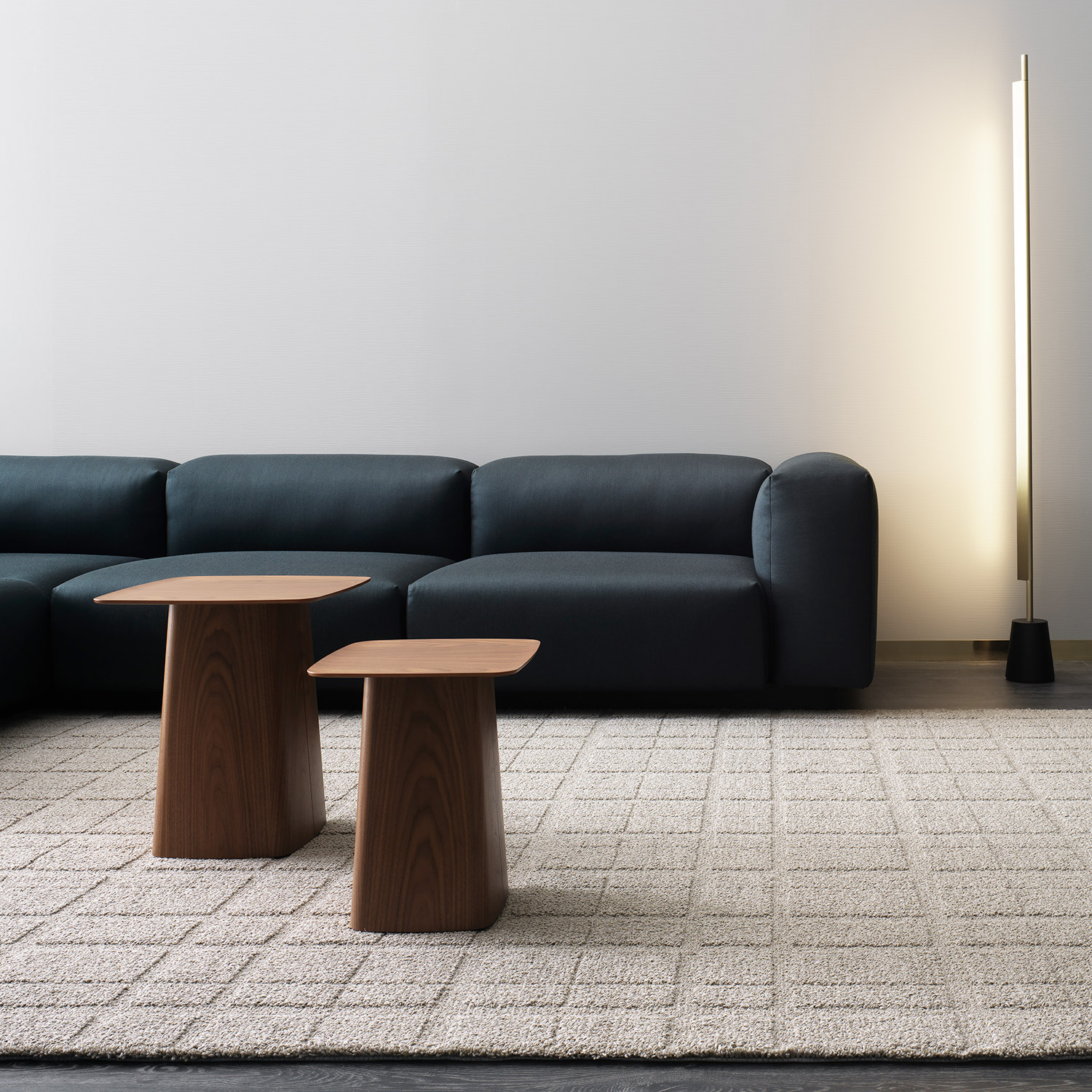 neutral wool rug, low navy sofa and modern wooden coffee tables