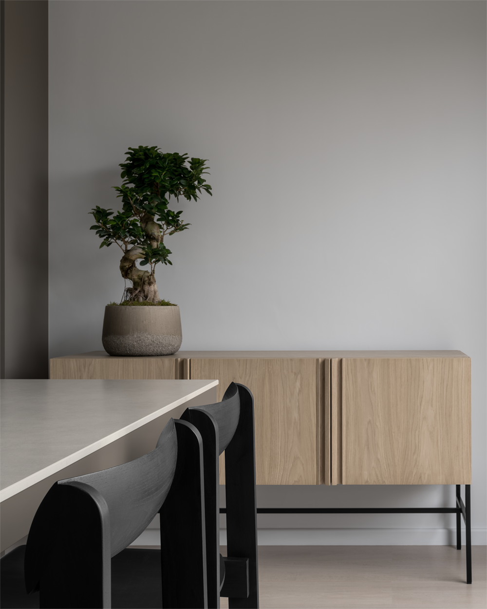 Minimalist Japanese inspired dining room in Surrey Hills with bleached oak floor, white walls, sintered stone bespoke dining table, Scandinavian black oak dining chairs, oak sideboard and bonsai tree.
