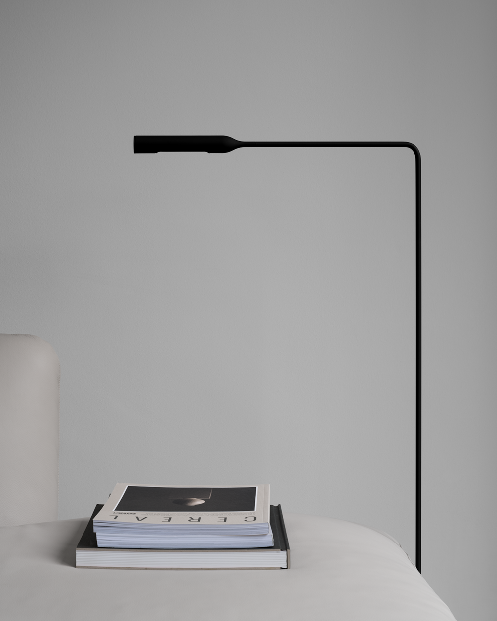 Detail of minimal light grey leather sofa, black metal floor lamp and Cereal magazines.
