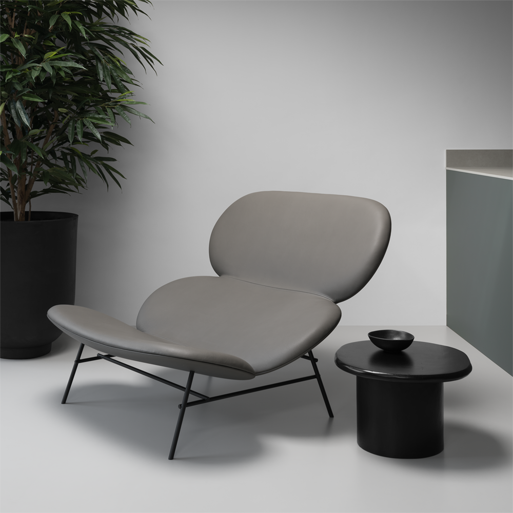Minimalist Japanese style chaise longue in grey leather, large black planter with tree and blackened oak side table.