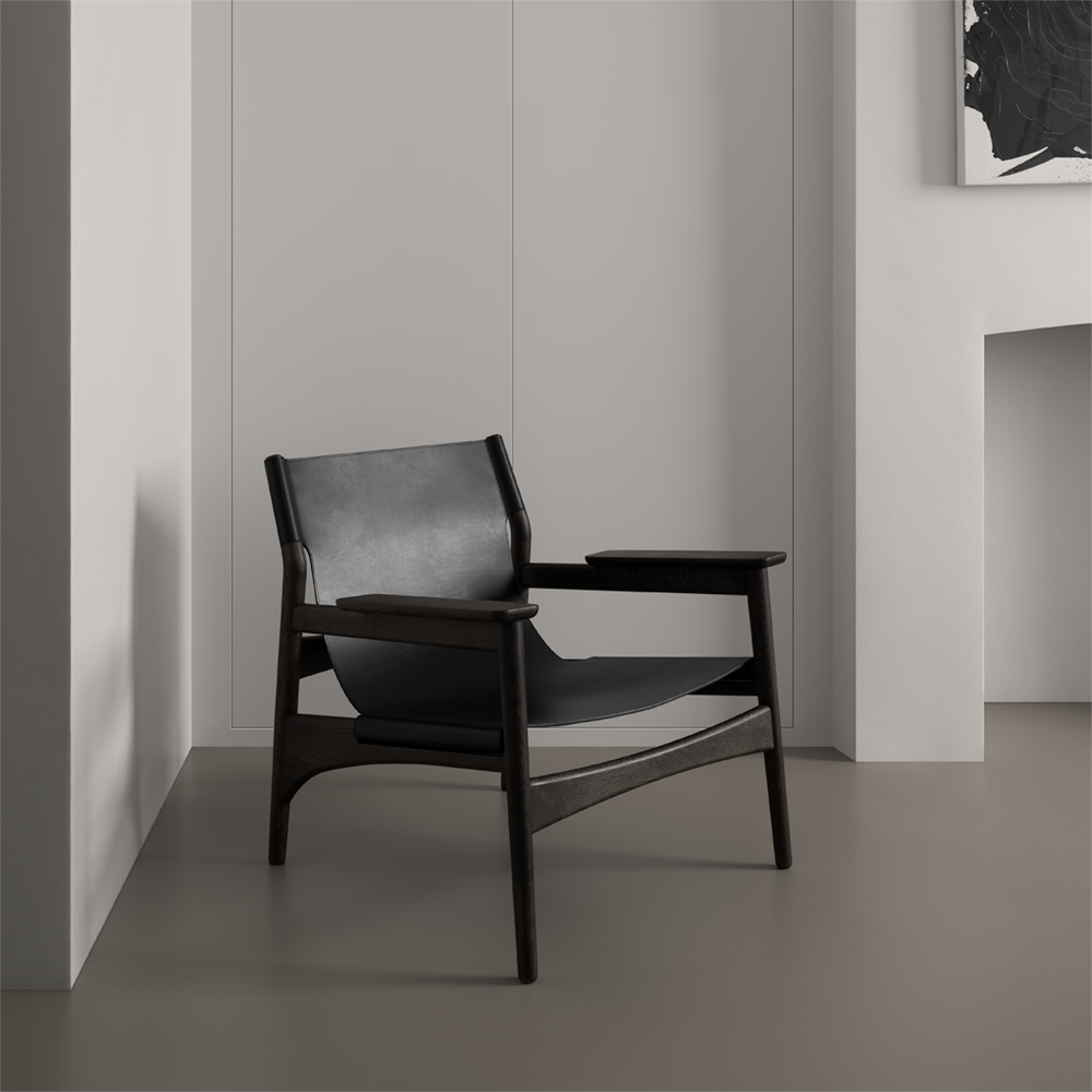 Minimal Japanese armchair in smoked oak and black leather in front of custom built-in white storage.