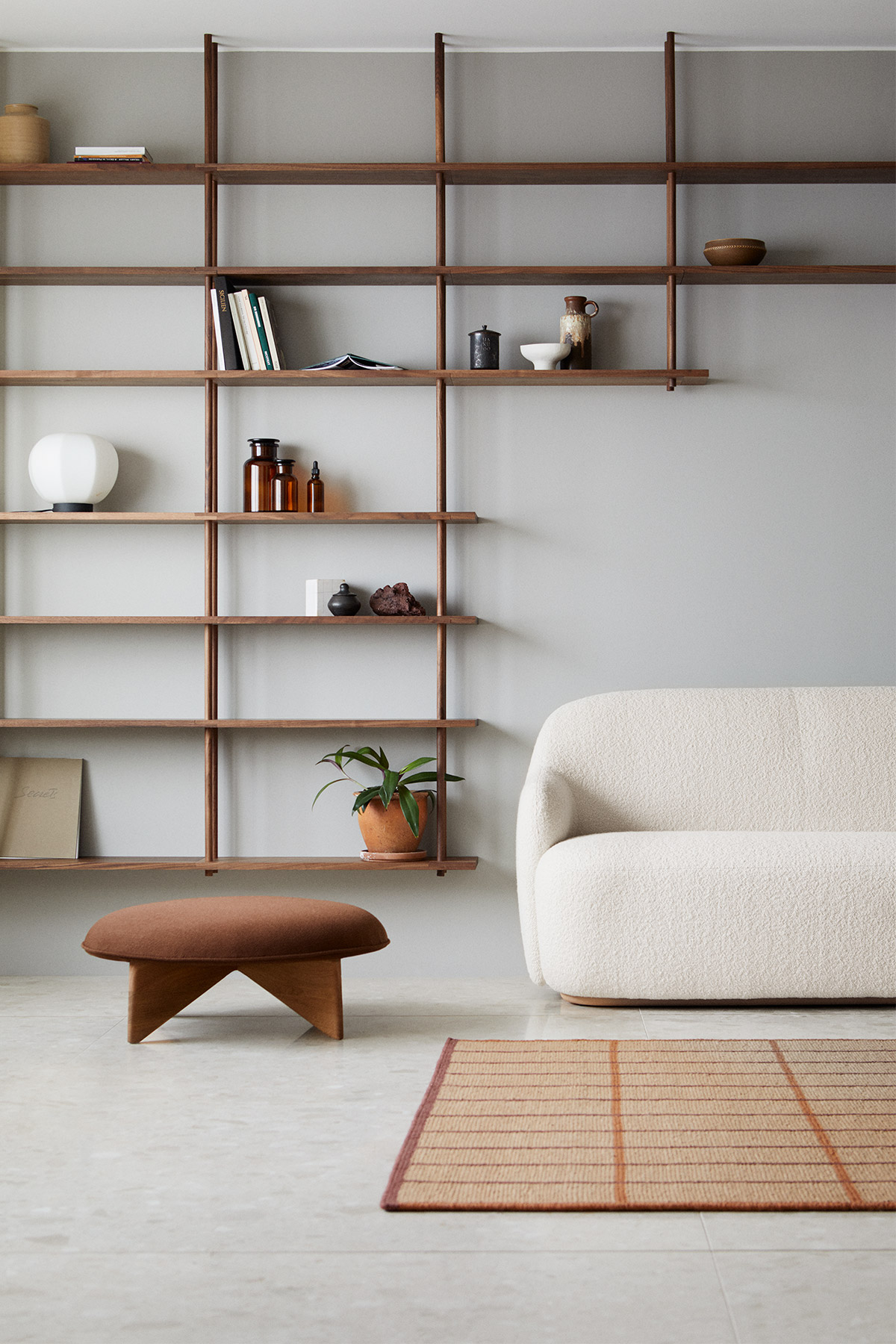 A calm Japanese interior with walnut wood shelving and cream sofa