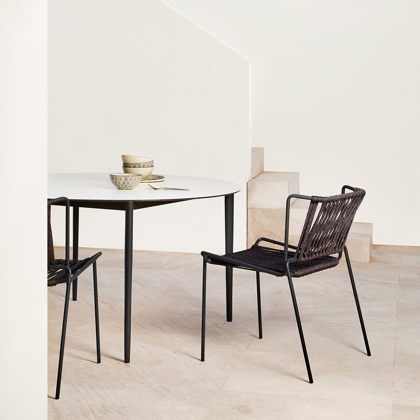Out_line outdoor chair in black metal and rope with Nude outdoor table in black metal and white ceramic in white courtyard