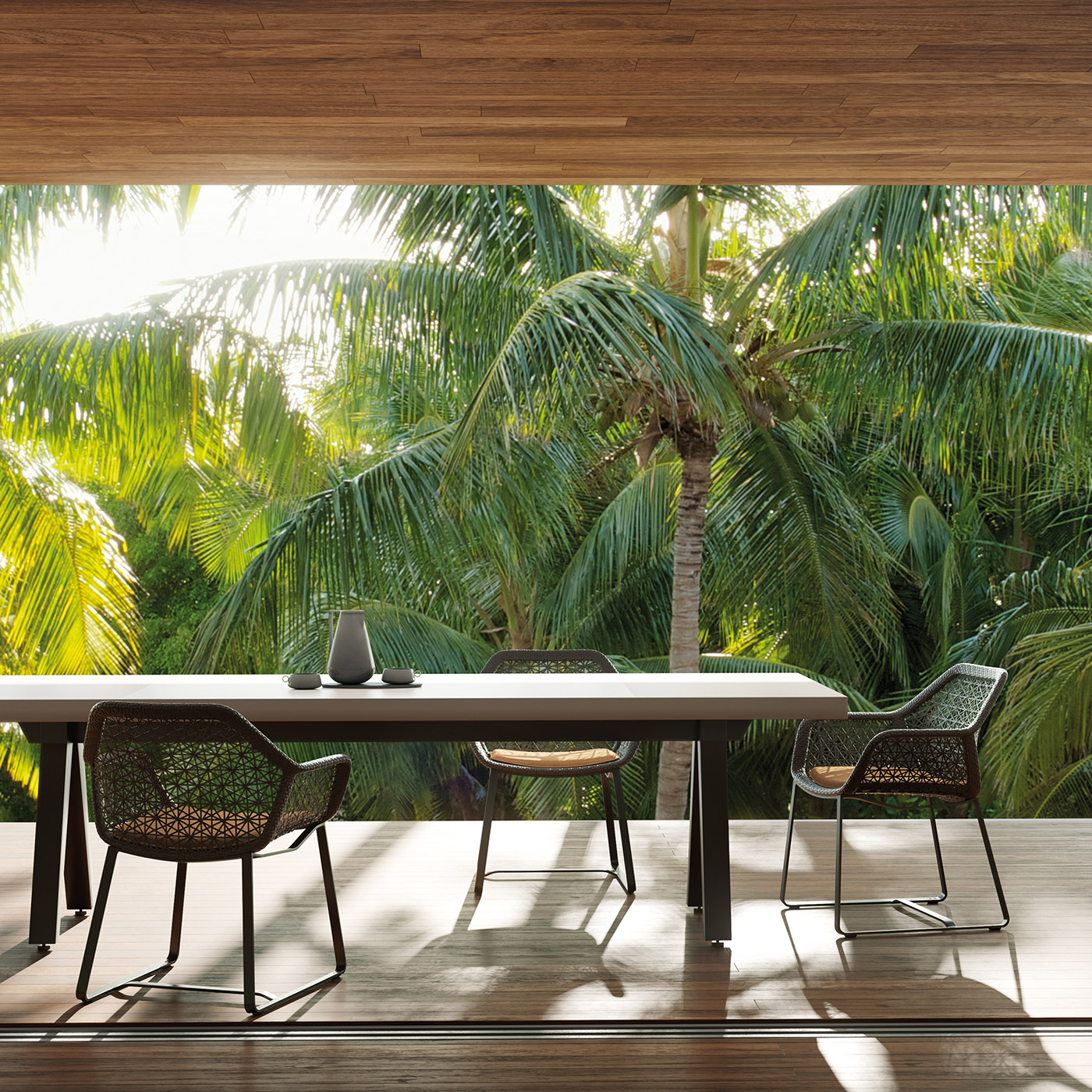 Maia outdoor dining armchair in black mesh with Vieques outdoor dining table in aluminium on a modern teak terrace overlooking palm trees