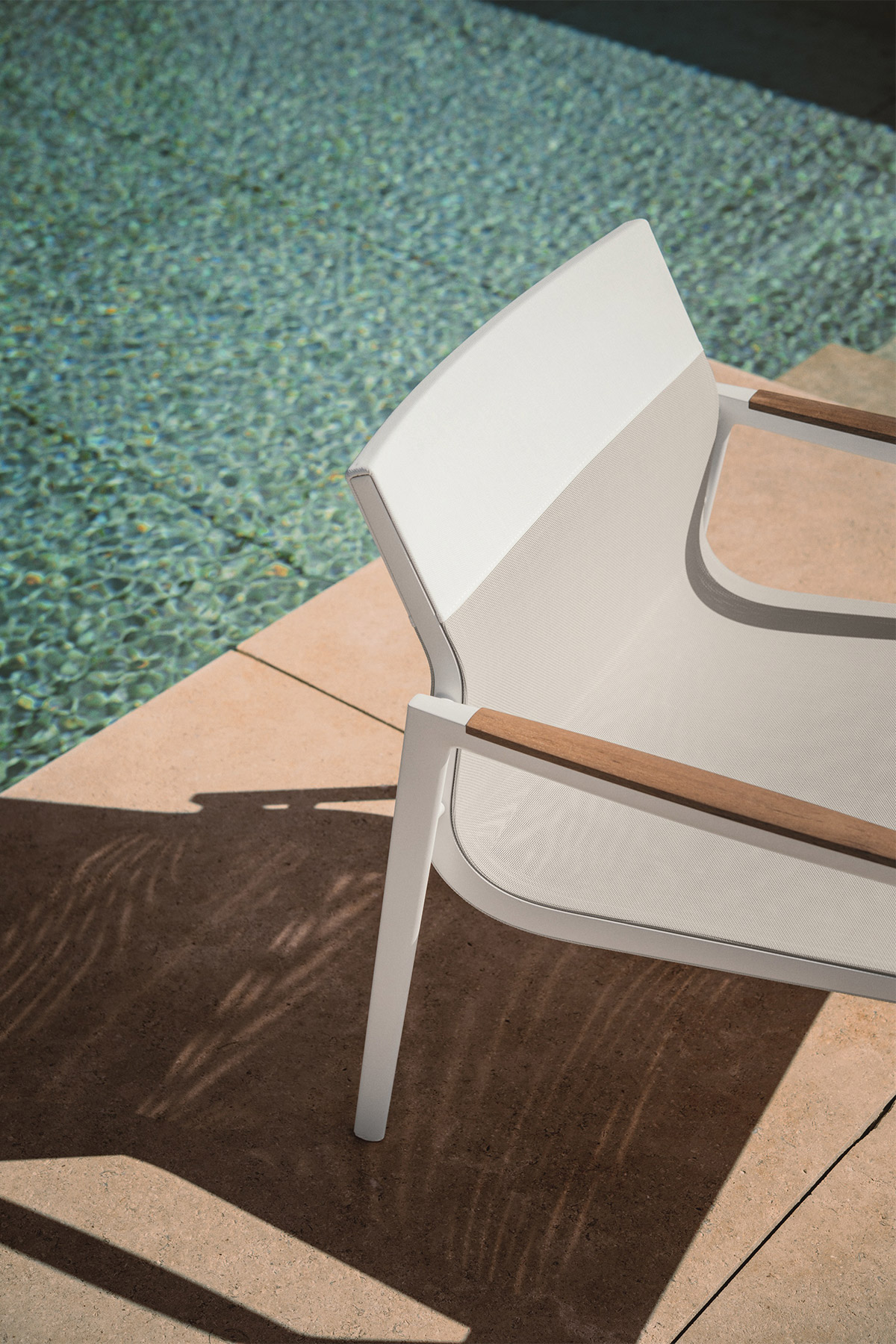 Modern white metal and teak outdoor dining Dean armchair by Dedon next to modern swimming pool