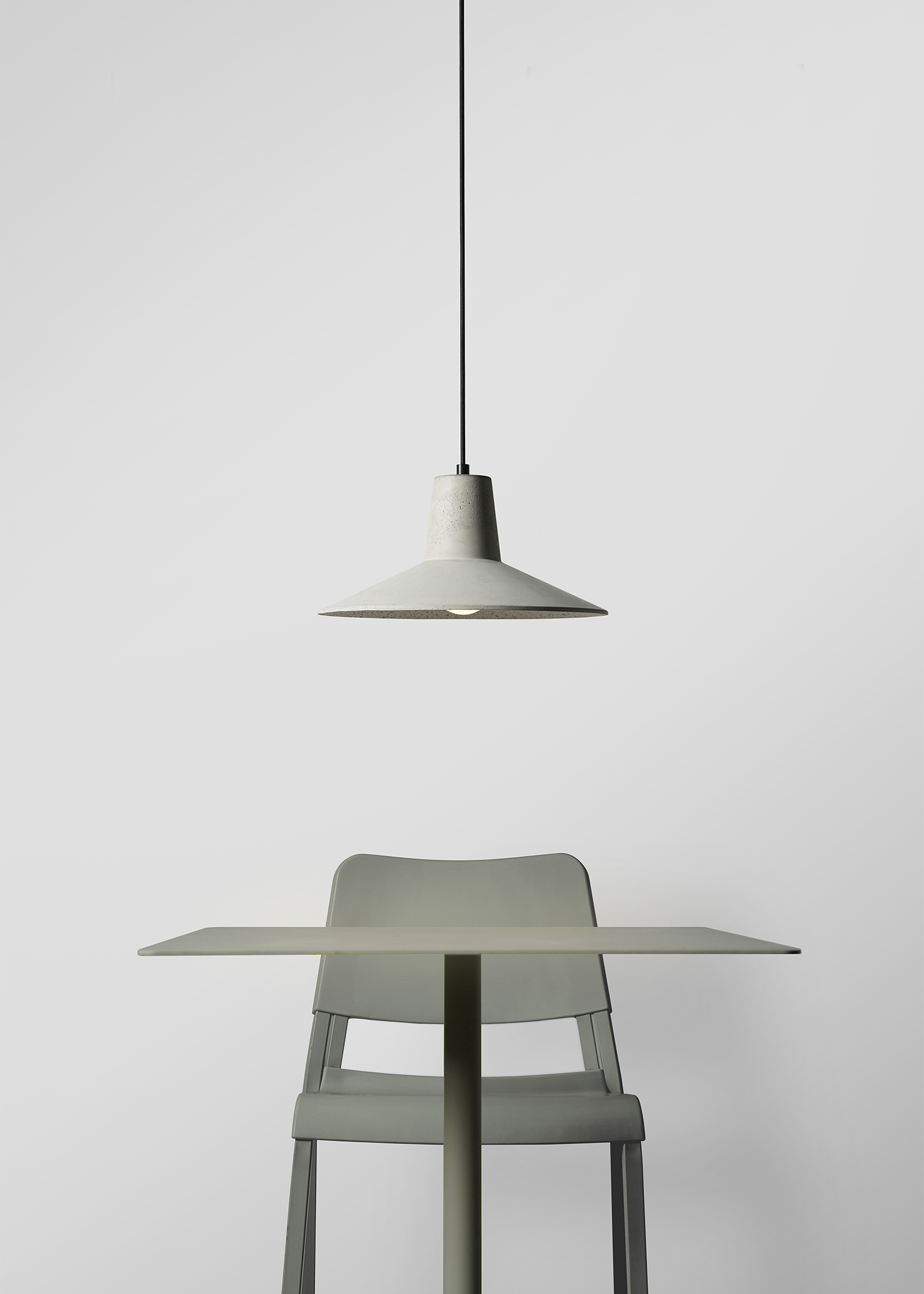 minimal concrete pendant light above sage green metal table and chair