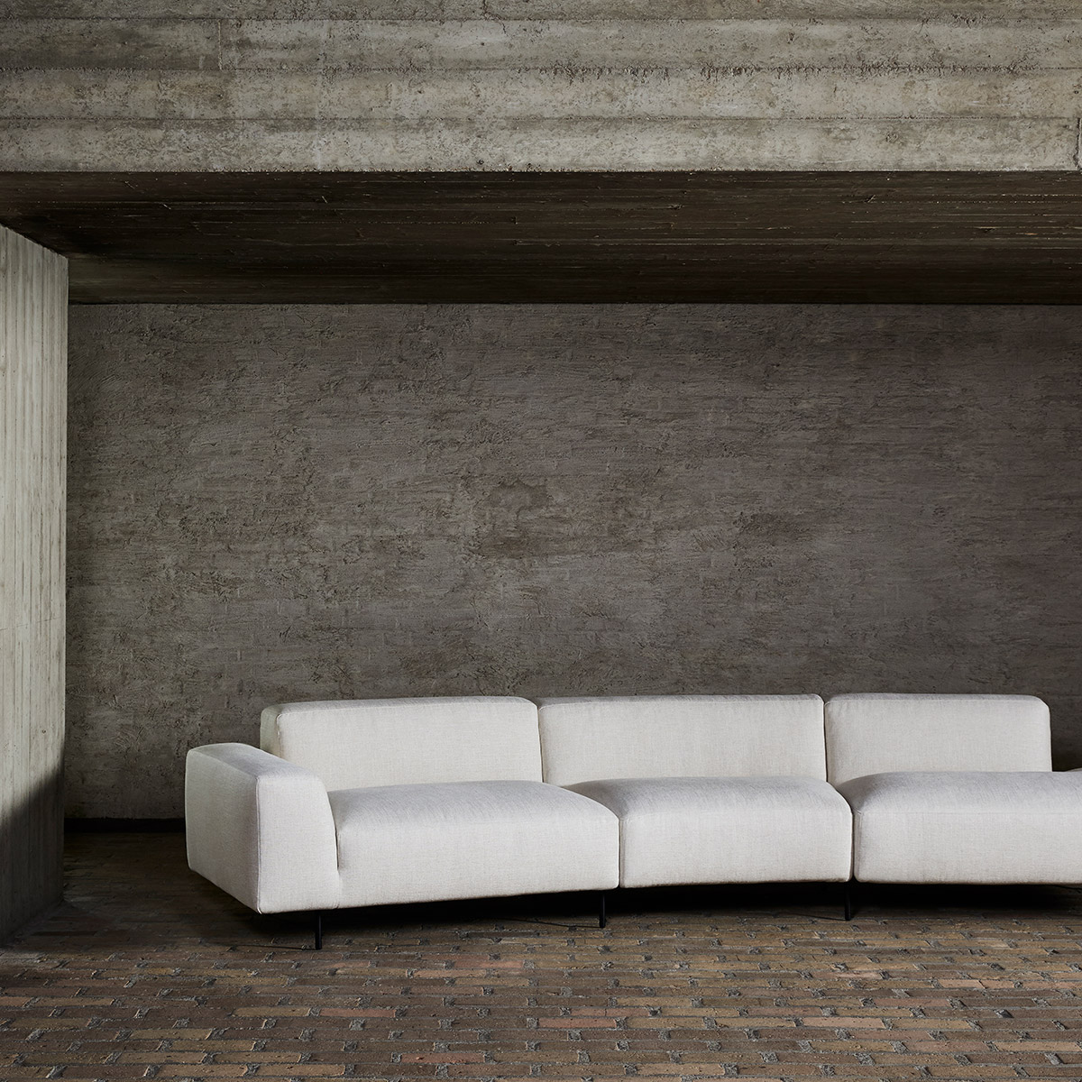 Endless sofa by Bensen in cream fabric against a concrete wall