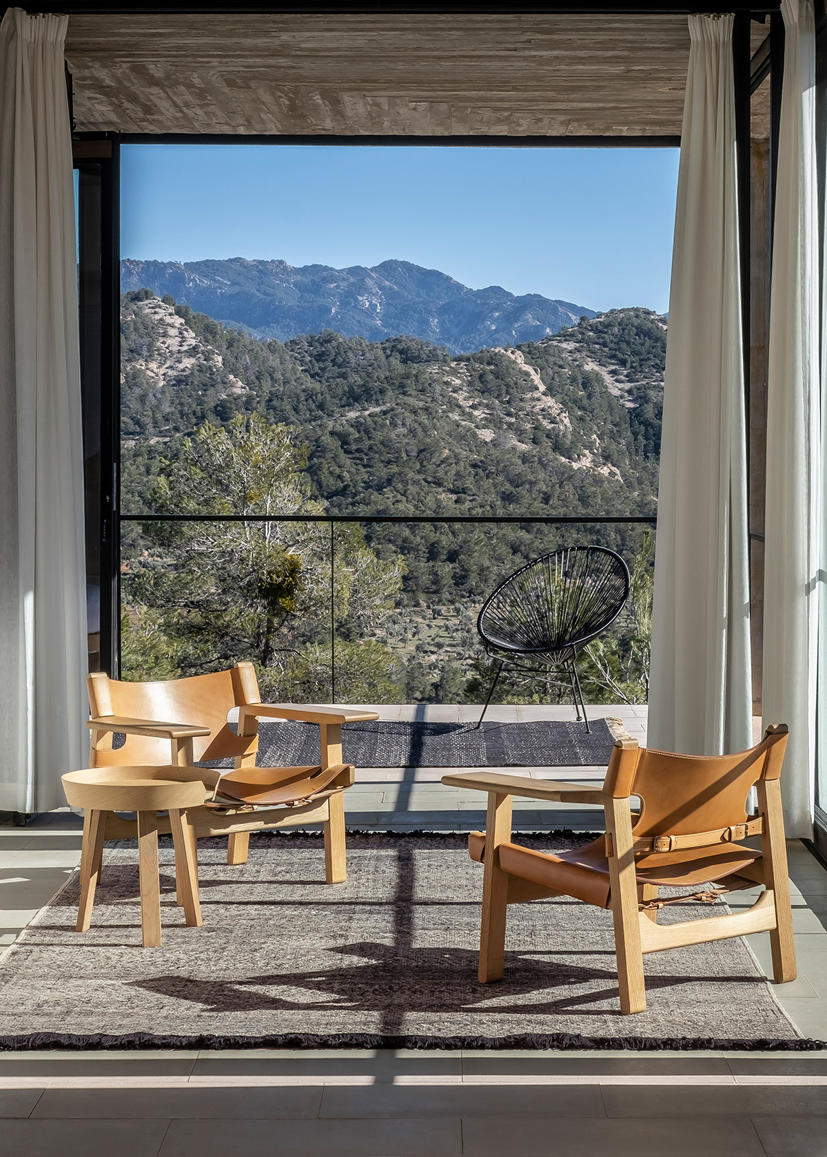 Telares rug and Spanish chair in modern concrete room with view of mountains