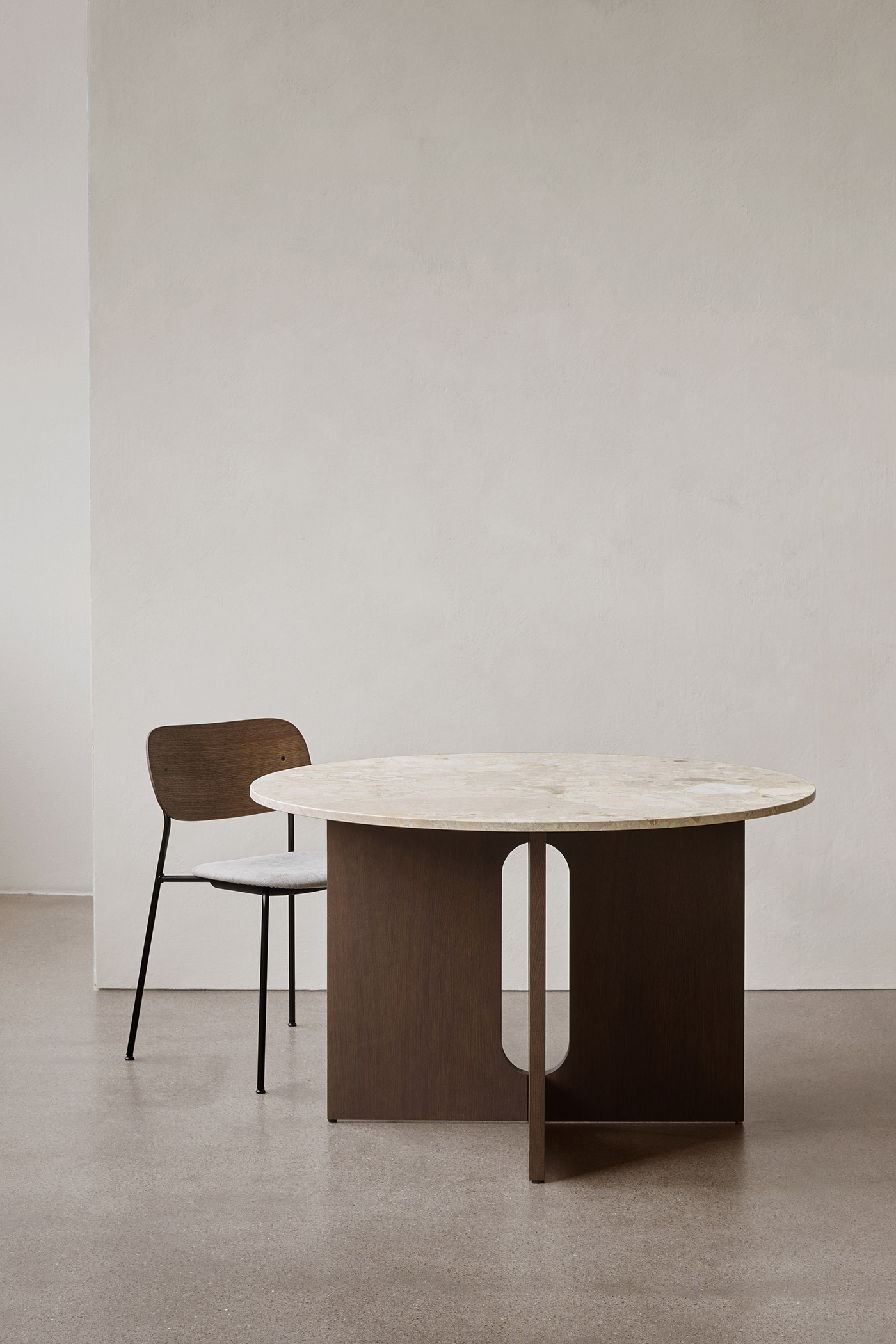 Minimal dark wooden dining table and chair against cream wall