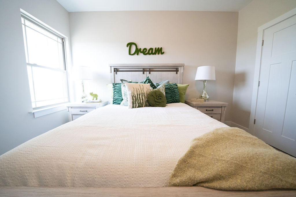 Close-up of bed in master bedroom with overhead sign that says "Dream"