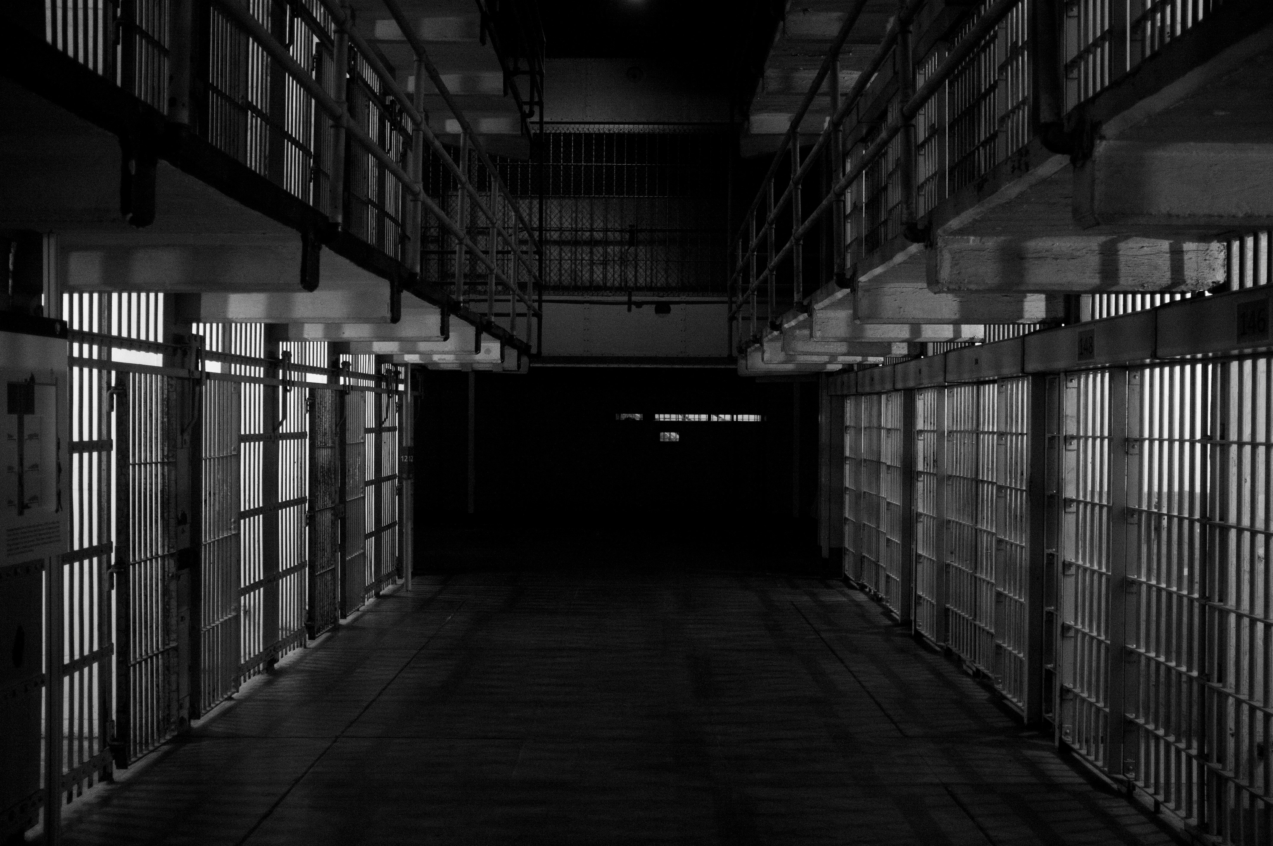prison cell block hallway with rows of barred cells